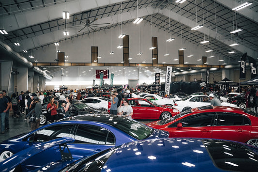 a group of people looking at cars in a showroom
