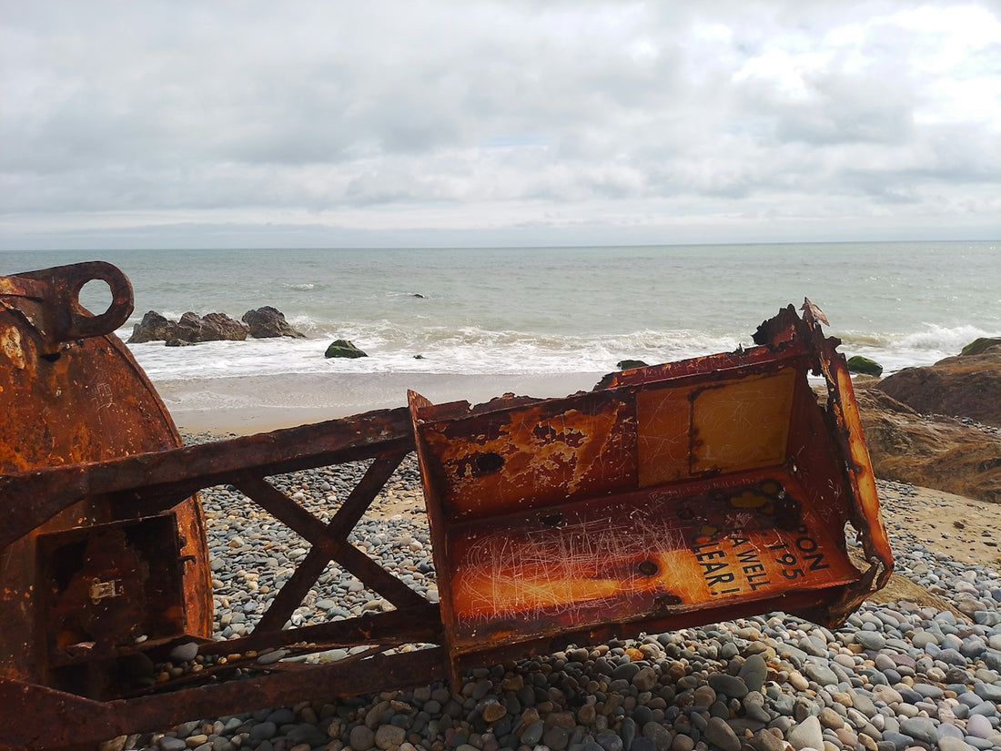 A rusted metal bench sitting on top of a rocky beach