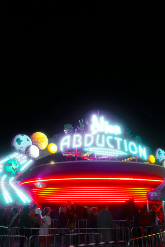 A carnival ride at night with people standing around