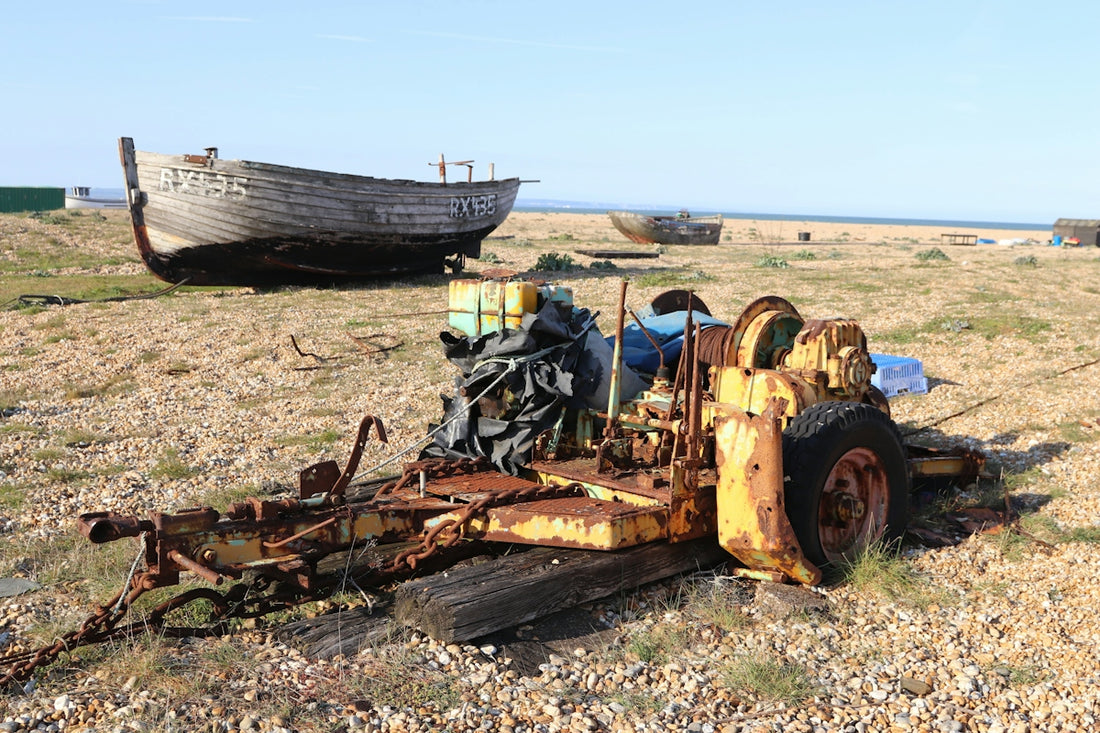 An old, rusty cart sits by abandoned boats