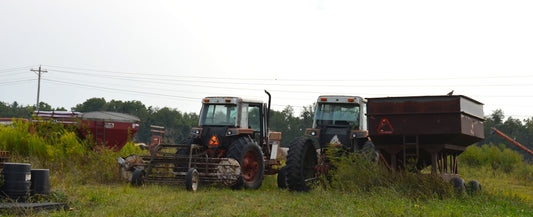 Two tractors and farm equipment in grassy field