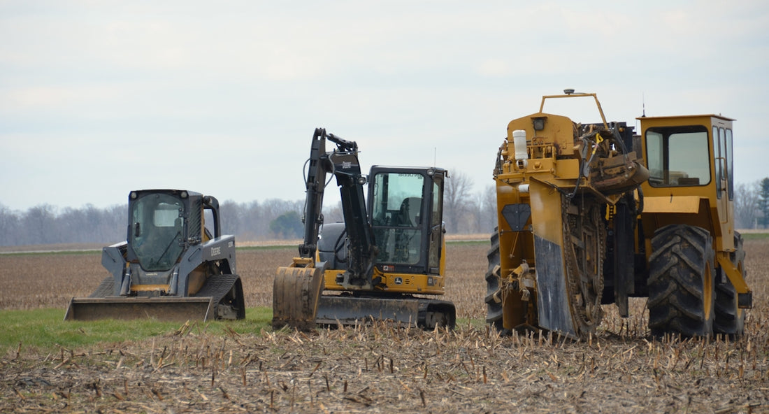 Three construction vehicles parked in a field