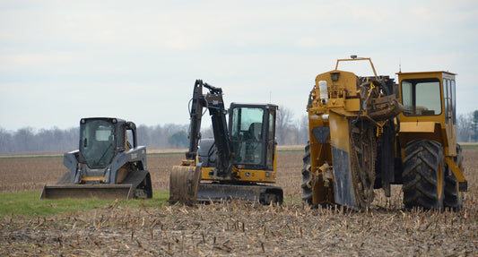 Three construction vehicles parked in a field